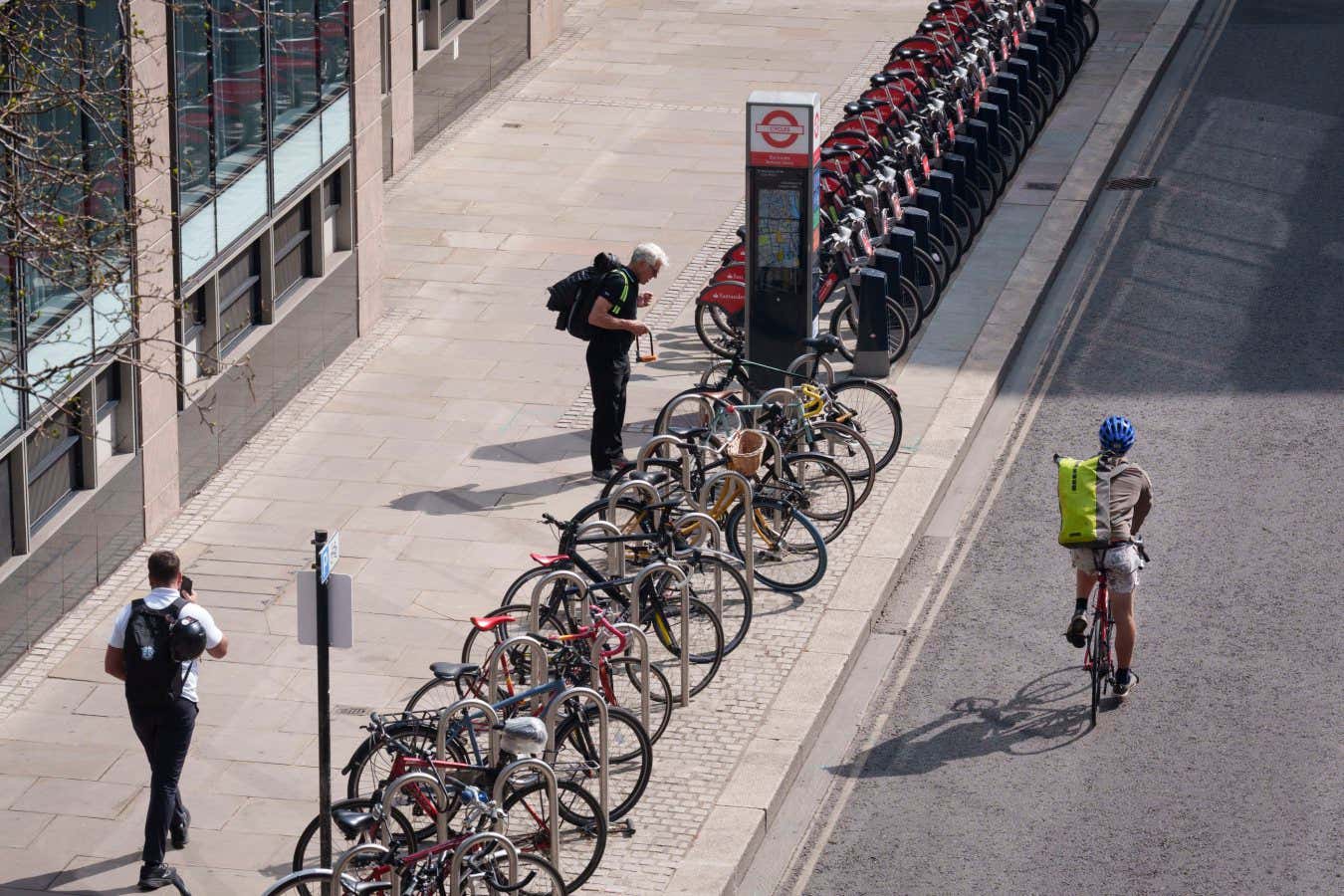 A cyclist unlocks his bike on Silk Street in the City of London, the capital