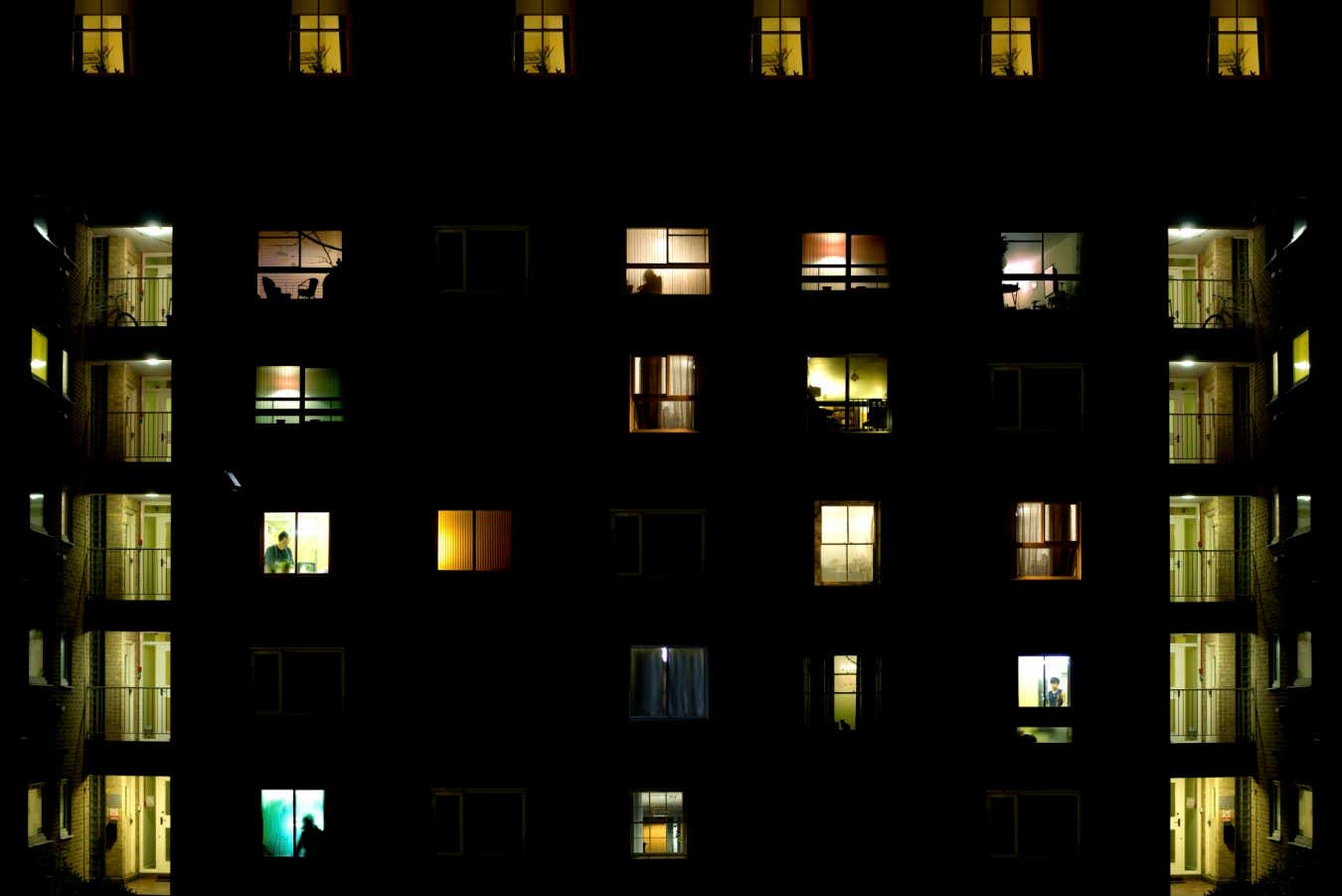 Block of flats Description Block of flats during night time with many figures in the windows and symmetrical staircase on both sides lit in green