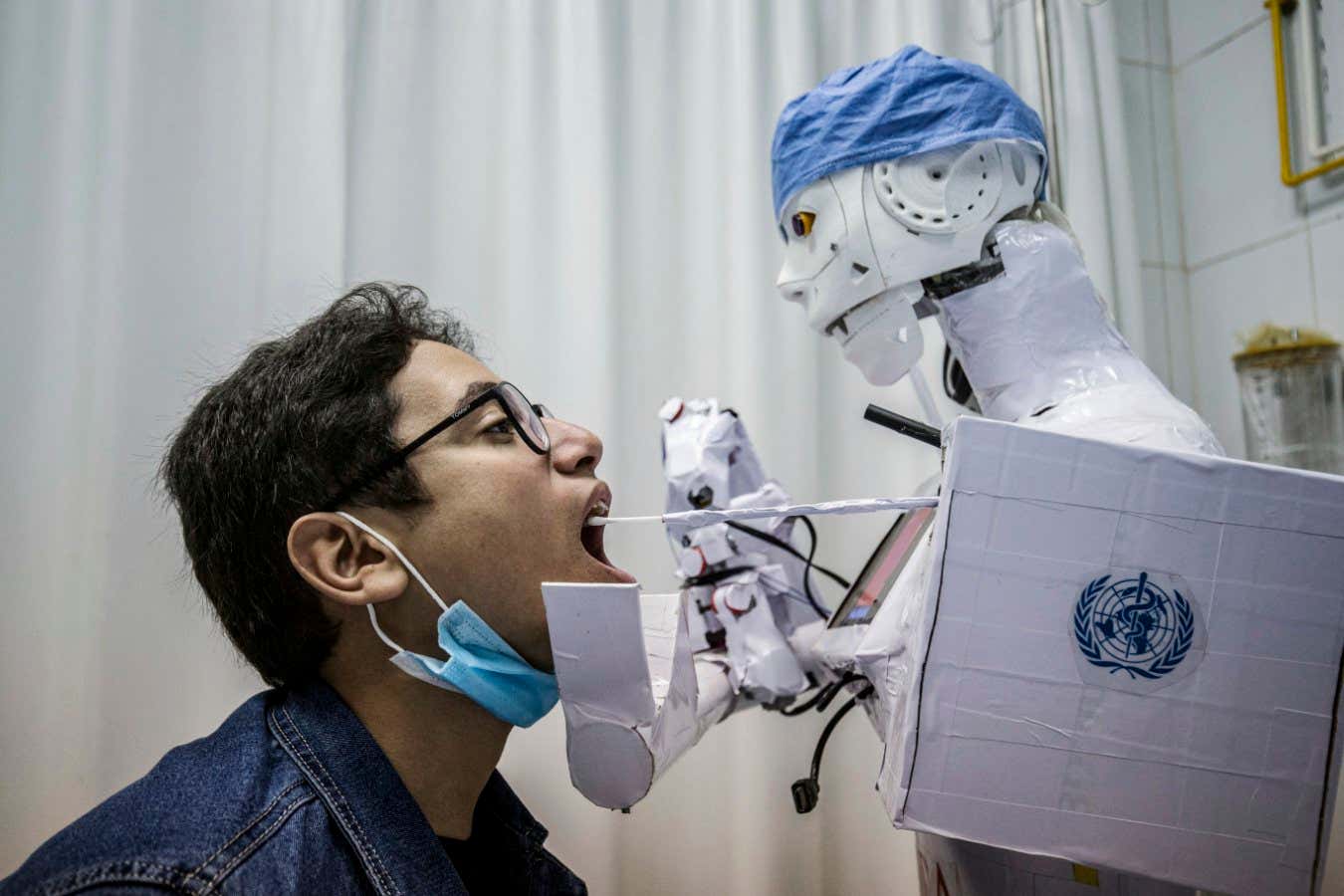 TOPSHOT - A prong extending from the CIRA-03 remote-controlled robot prototype approaches the mouth of a volunteer to extract a throat swab sample, as part of a self-funded project to assist physicians in running tests on suspected COVID-19 coronavirus patients in a bid to limit human exposure to disease-carriers, at a private hospital in Egypt