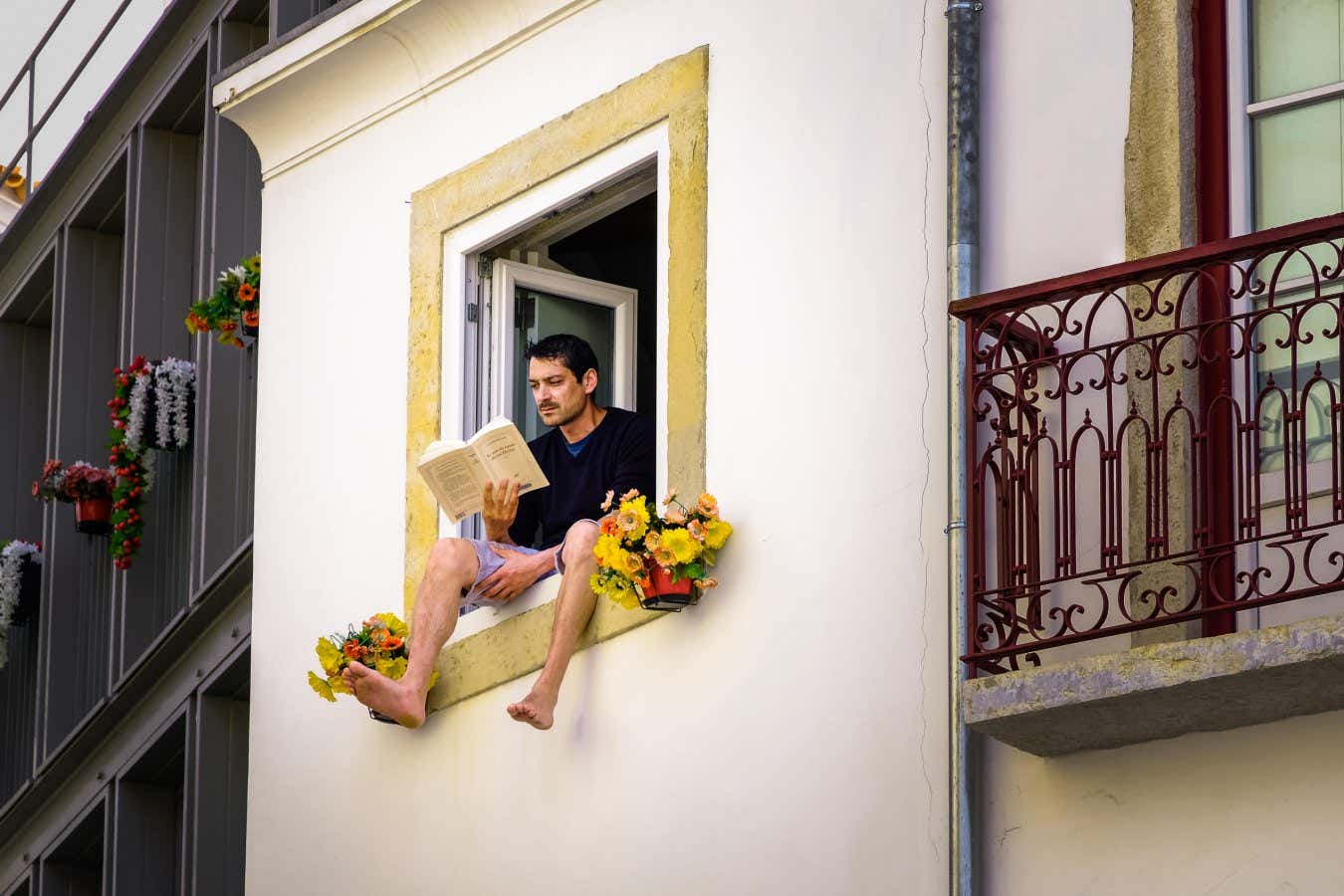 MP46X7 Man sitting on the window seal of an open window reading; man