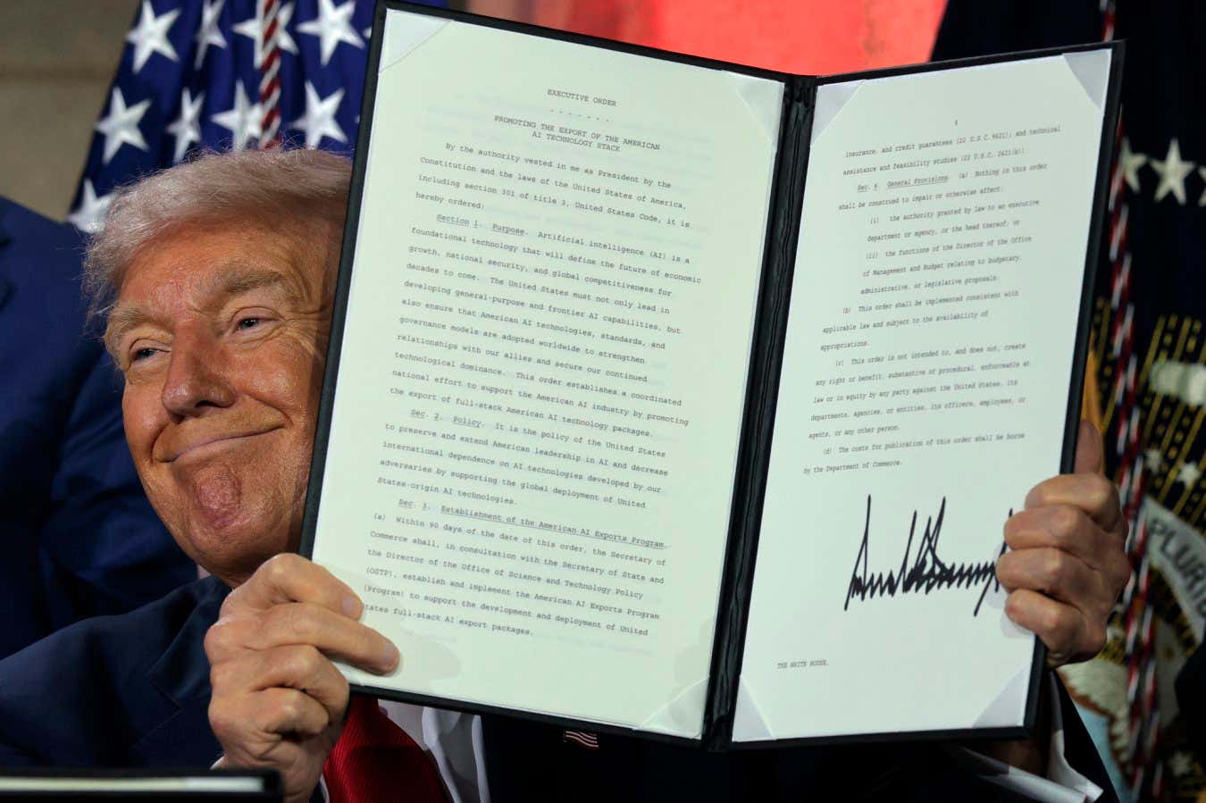 Donald Trump displays a signed executive order at an AI summit