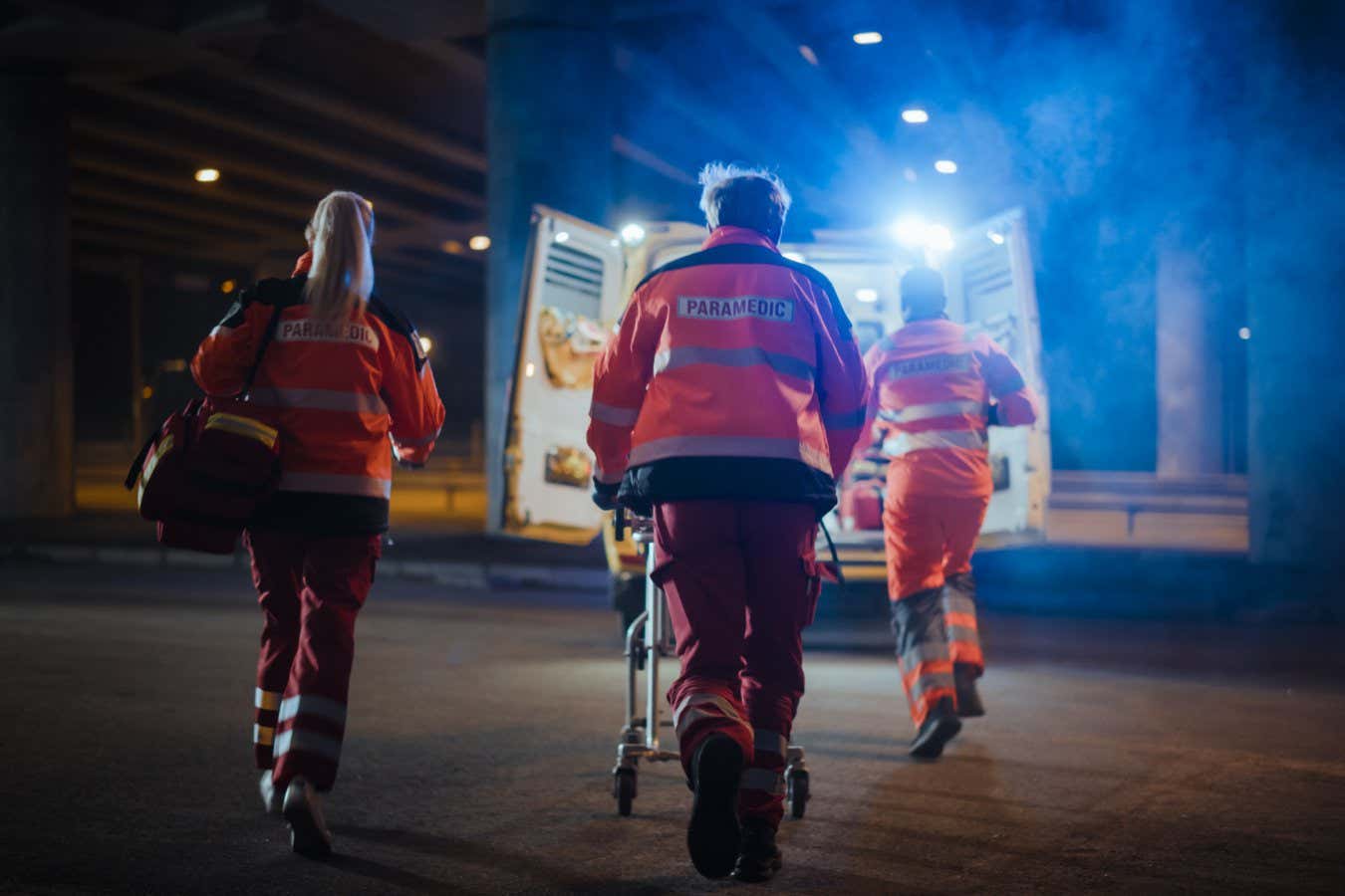 Team of EMS Paramedics React Quick to Provide Medical Help to Injured Patient and Get Him in Ambulance on a Stretcher. Emergency Care Assistants Arrived on the Scene of a Traffic Accident on a Street.