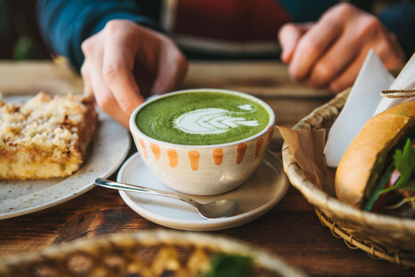A close up of someone holding a cup of green tea with foam art