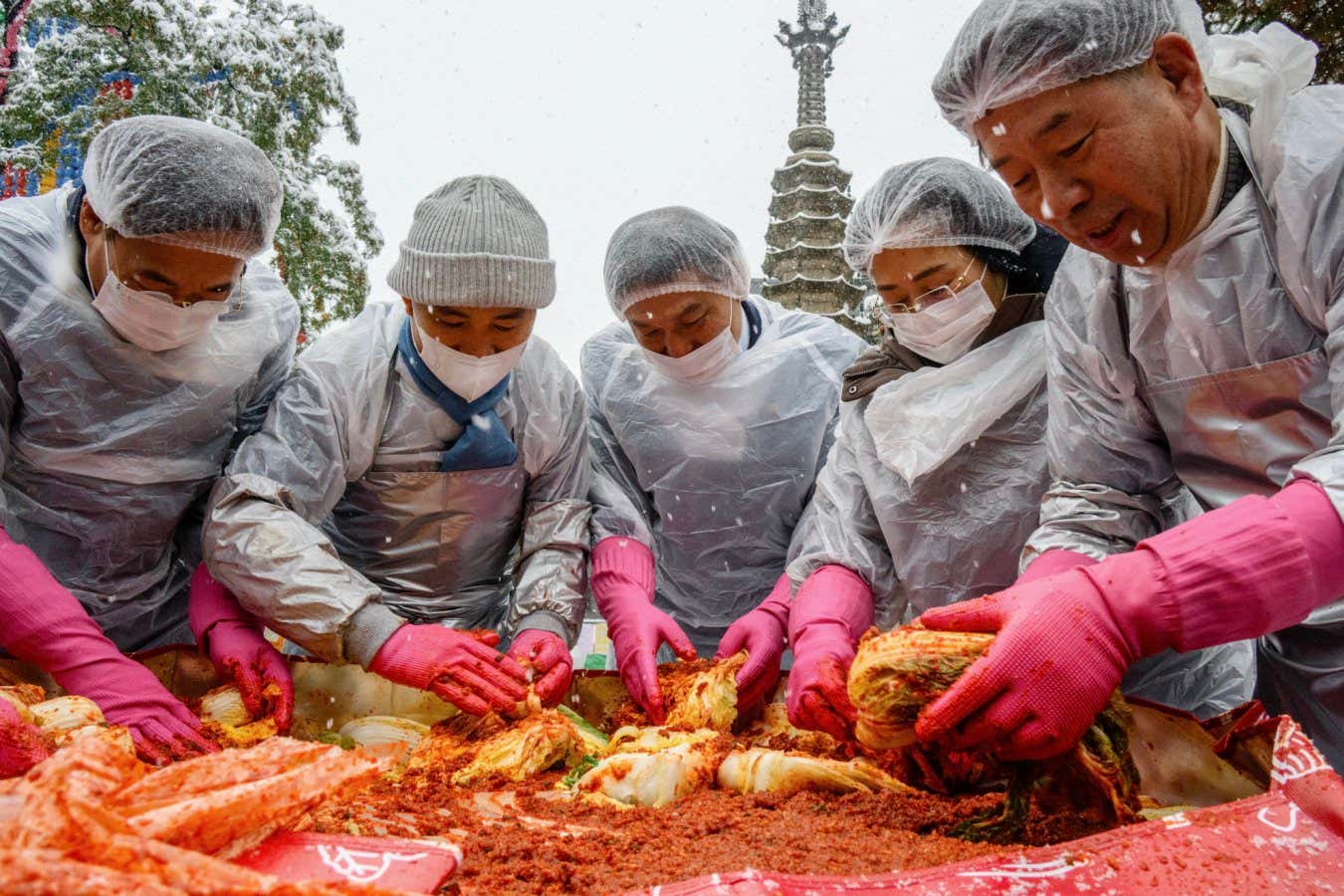 Participants prepare kimchi, a traditional Korean dish of spicy fermented cabbage and radish, during a kimchi making festival held amid snowfall at the Jogyesa Temple in Seoul on November 27, 2024. (Photo by ANTHONY WALLACE / AFP) (Photo by ANTHONY WALLACE/AFP via Getty Images)