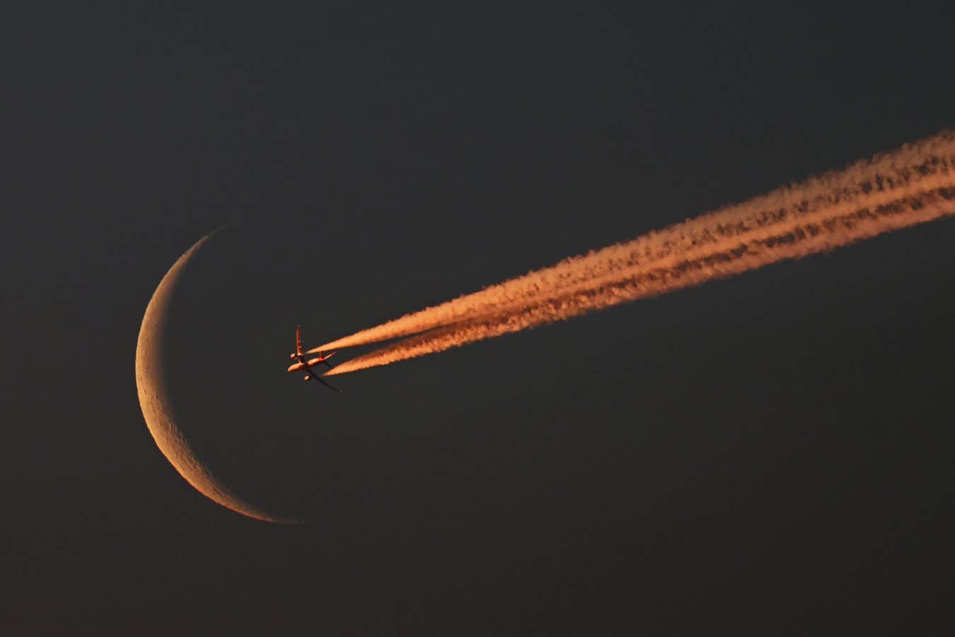 Crescent moon rise at dawn with passing passenger jet