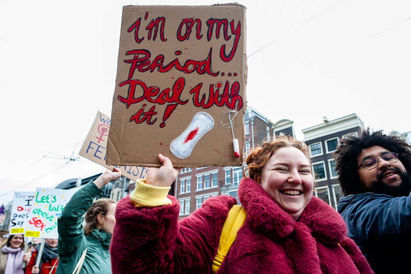 A woman is holding a placard with a sanitary towel with fake blood, during the Women