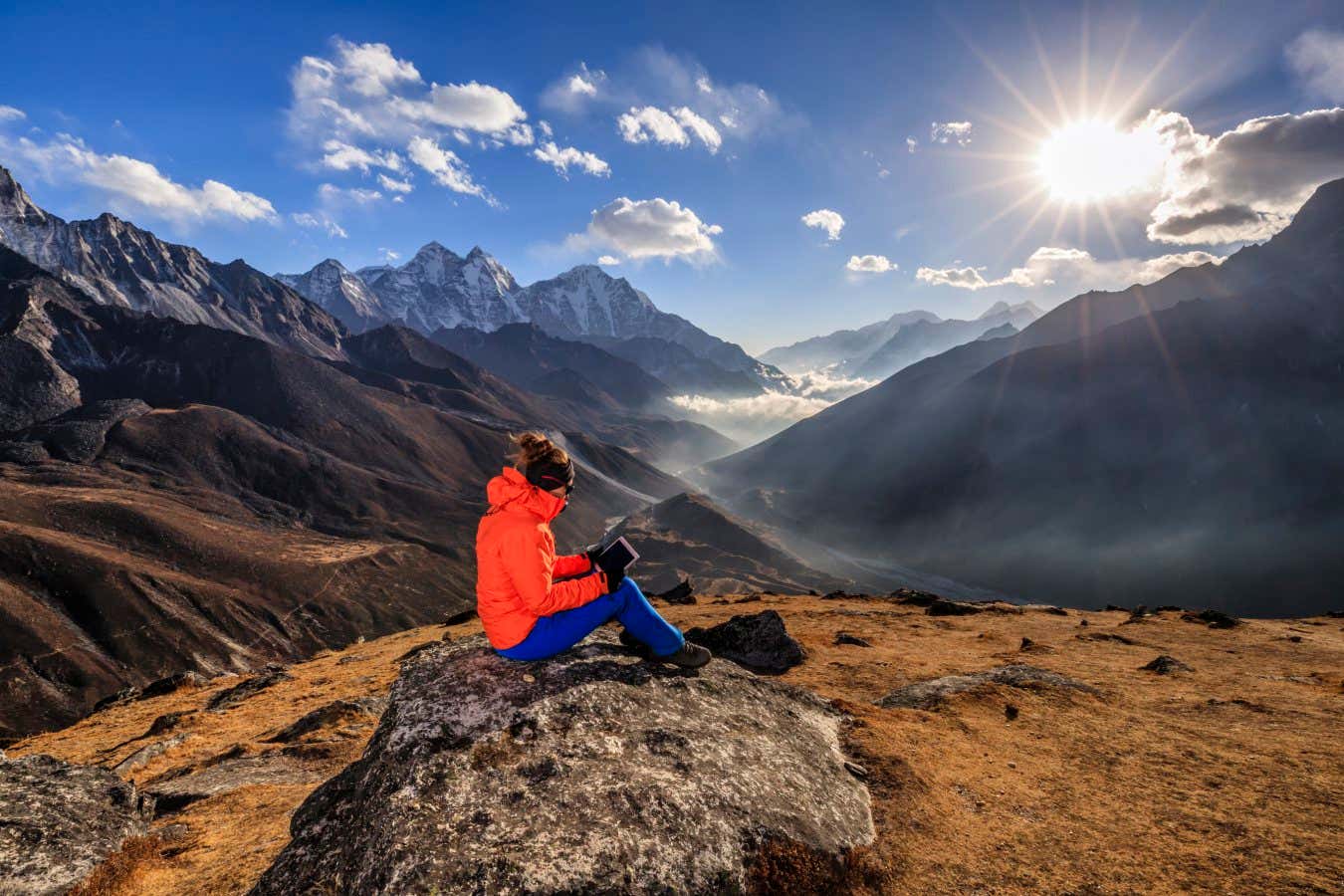 Young woman, wearing a orange jacket, is reading a book on an ebook reader during sunset over Himalayas. She is sitting on the top of a mountain and holding the e-reader.The afternoon sun on the background. Mount Everest National Park. This is the highest national park in the world, with the entire park located above 3,000 m ( 9,700 ft). This park includes three peaks higher than 8,000 m, including Mt Everest. Therefore, most of the park area is very rugged and steep, with its terrain cut by deep rivers and glaciers. Unlike other parks in the plain areas, this park can be divided into four climate zones because of the rising altitude. The climatic zones include a forested lower zone, a zone of alpine scrub, the upper alpine zone which includes upper limit of vegetation growth, and the Arctic zone where no plants can grow.