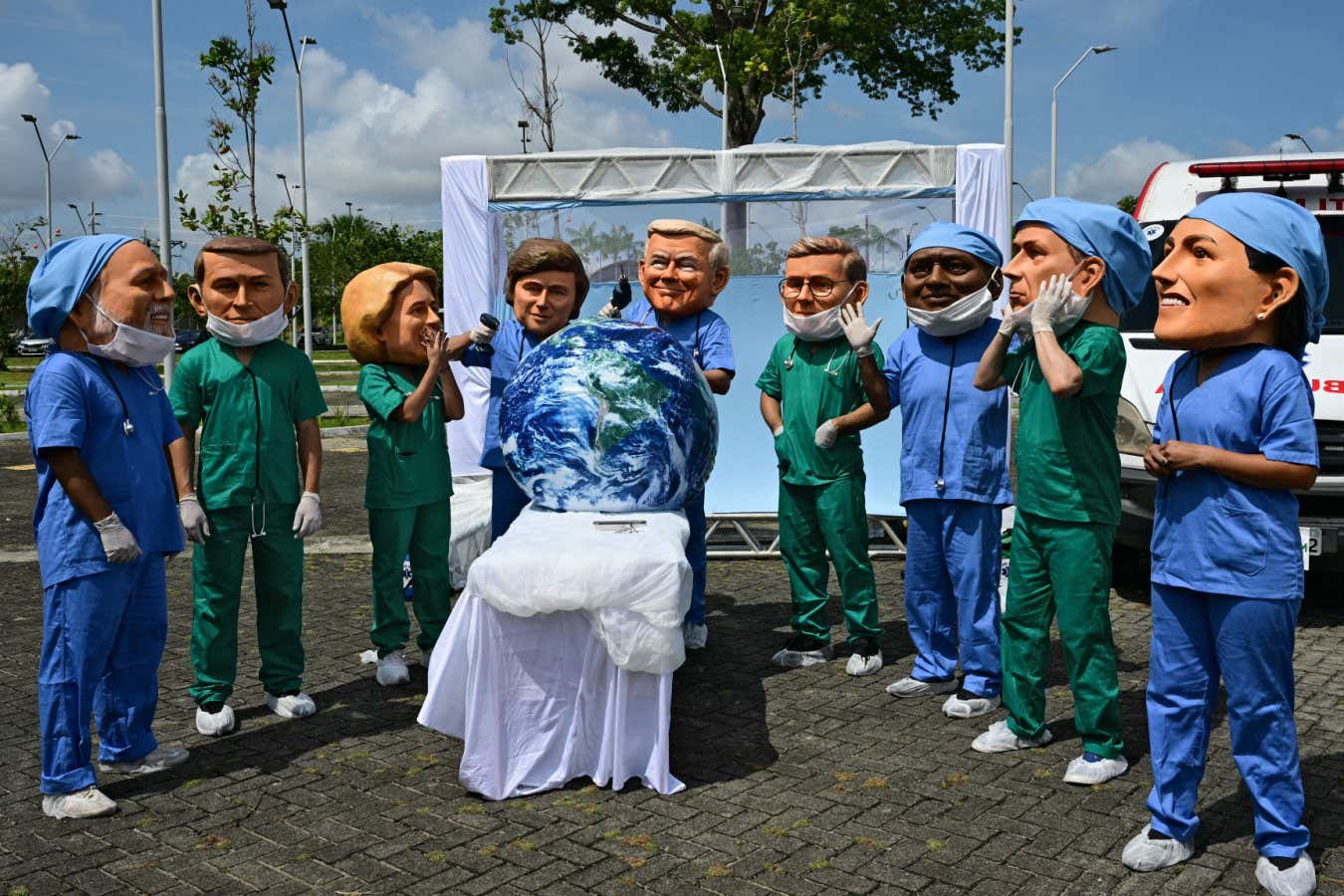 Oxfam activists wearing oversized masks representing (L to R) Brazil